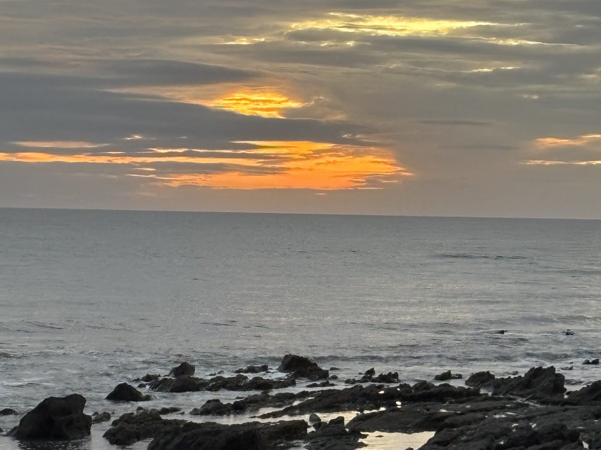 Coucher de soleil sur la mer, avec des rochers au bord de l’eau
